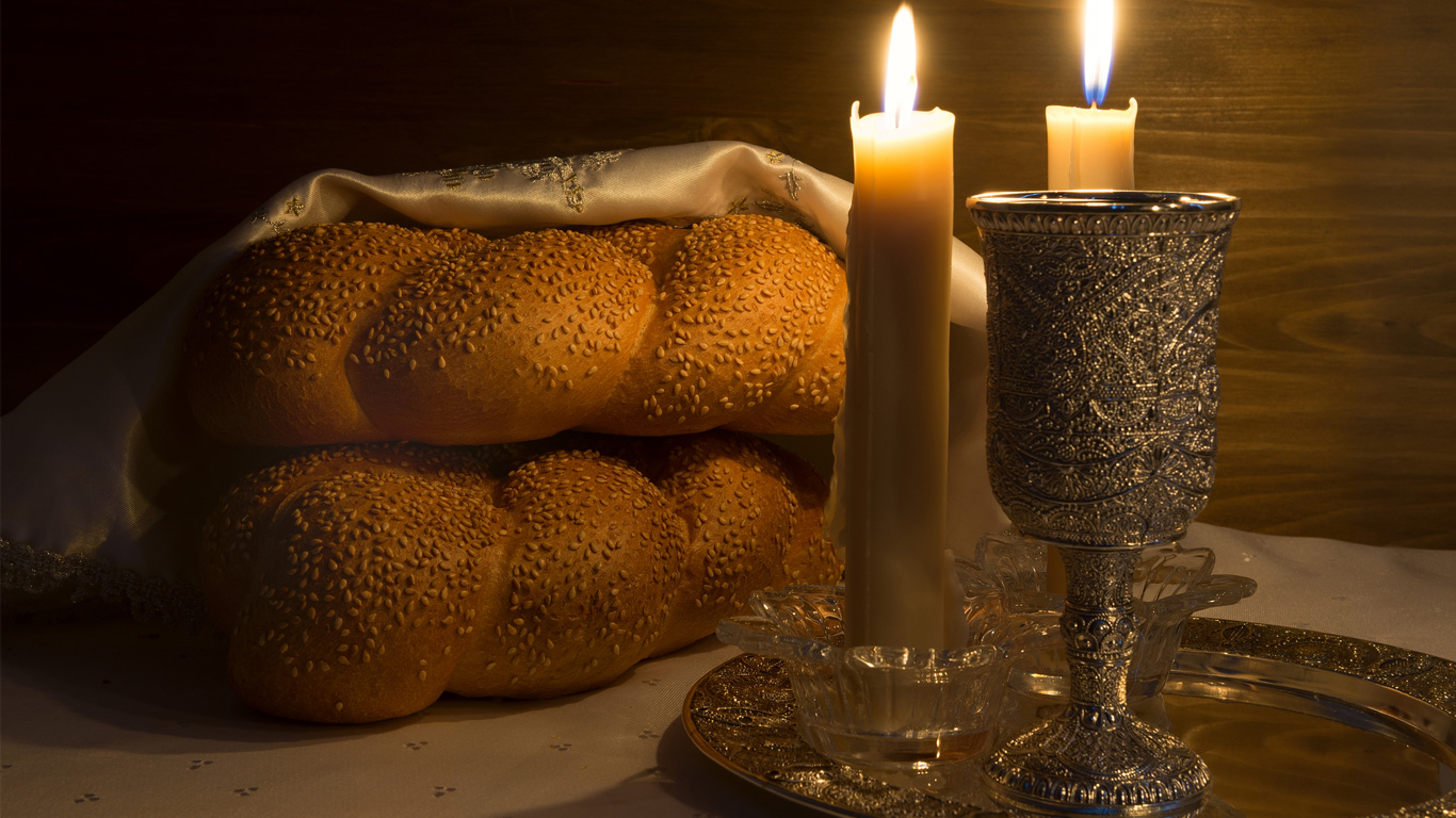 A Shabbat shalom wine, challahs and candles for a traditional Jewish Sabbath ritual.